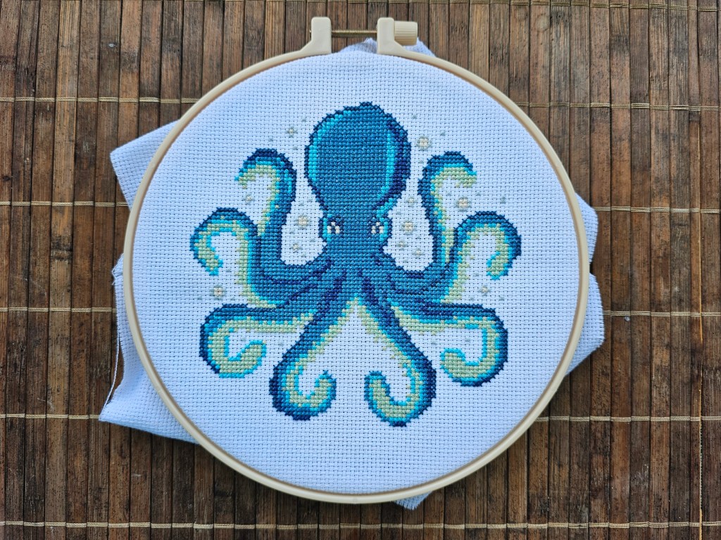 Completed blue and green octopus cross stitch design.