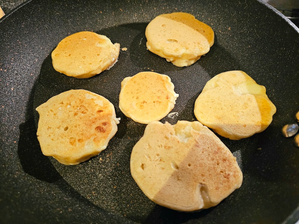 Apple fritters being fried on a non-stick pan.