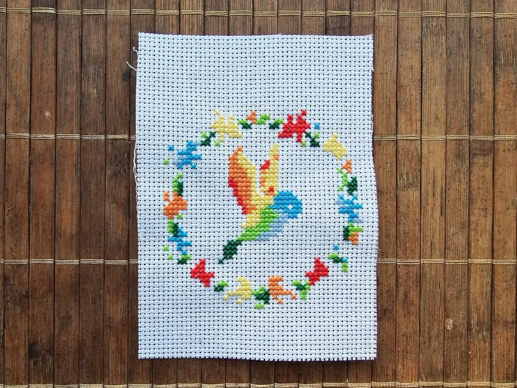 Nearly finished mini colourful hummingbird cross stitch design. Only brown details are missing.