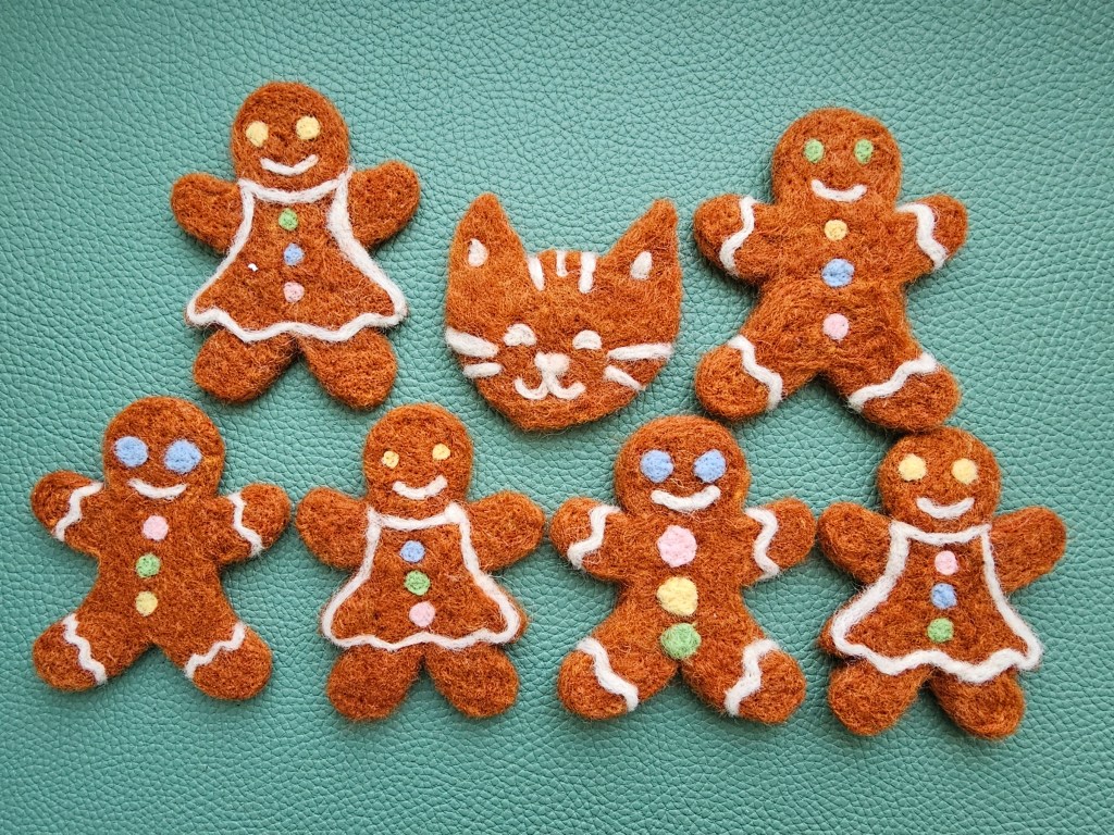 Finished felt gingerbread gift tags made with needle felting. There are 3 gingerbread men, 3 girls and a cat.