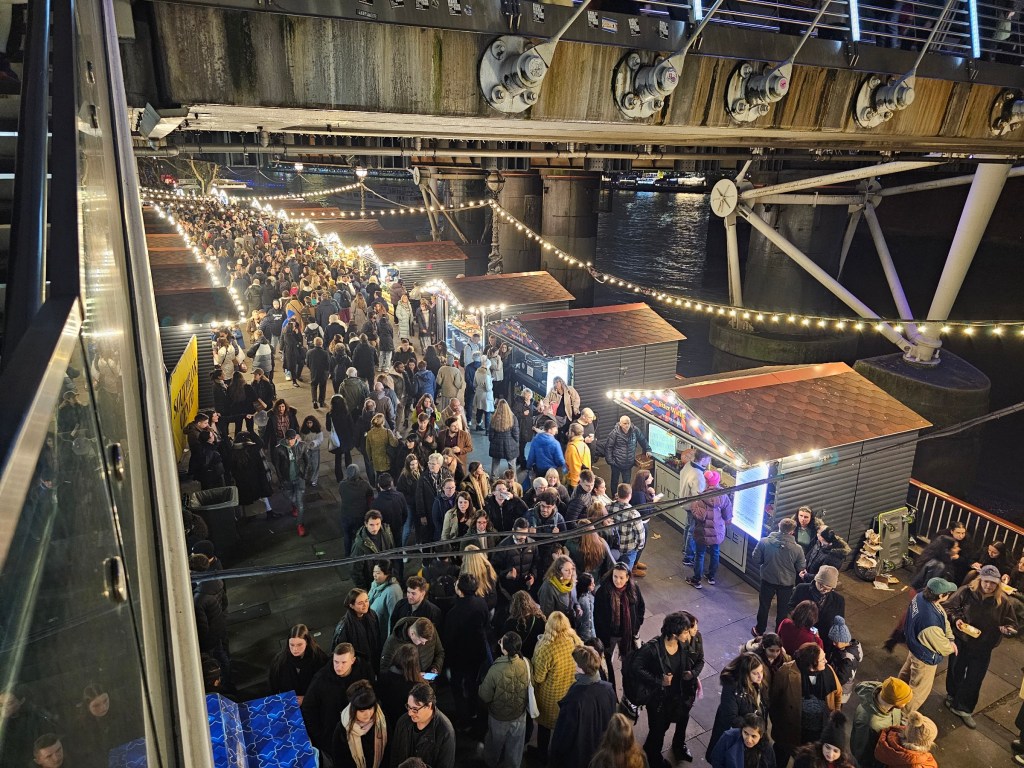 Two rows of Christmas Market stalls under a bridge at Southbank, London.
