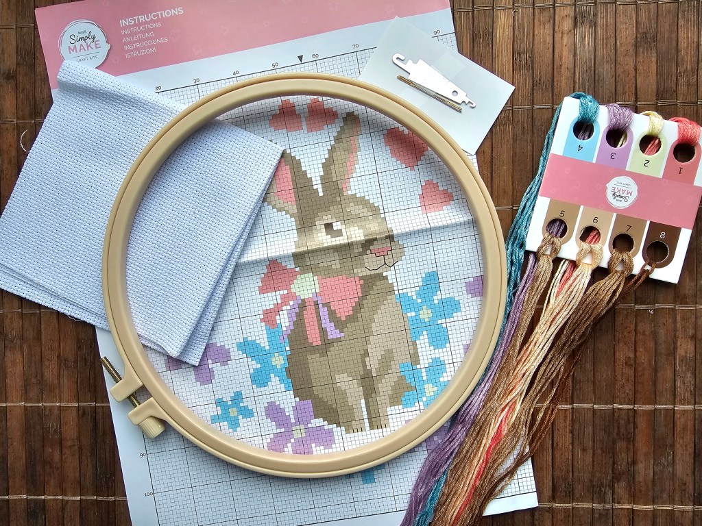Contents of an assorted DIY cross stitch kit with an Easter bunny design.