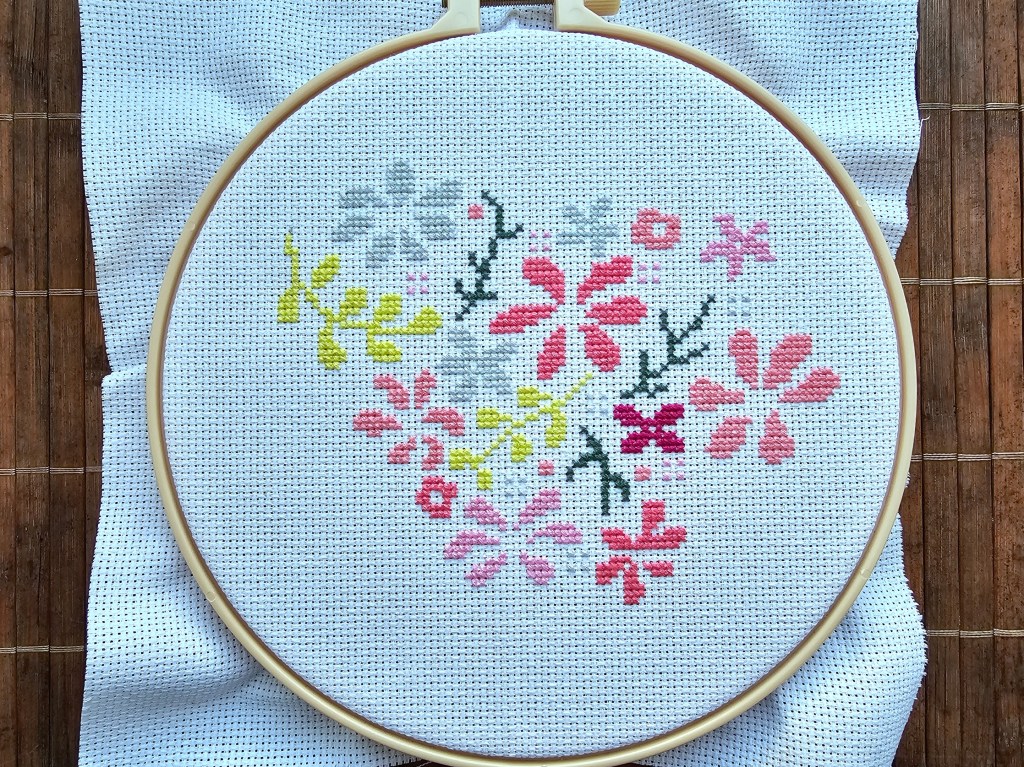 Partially completed floral heart cross stitch design.