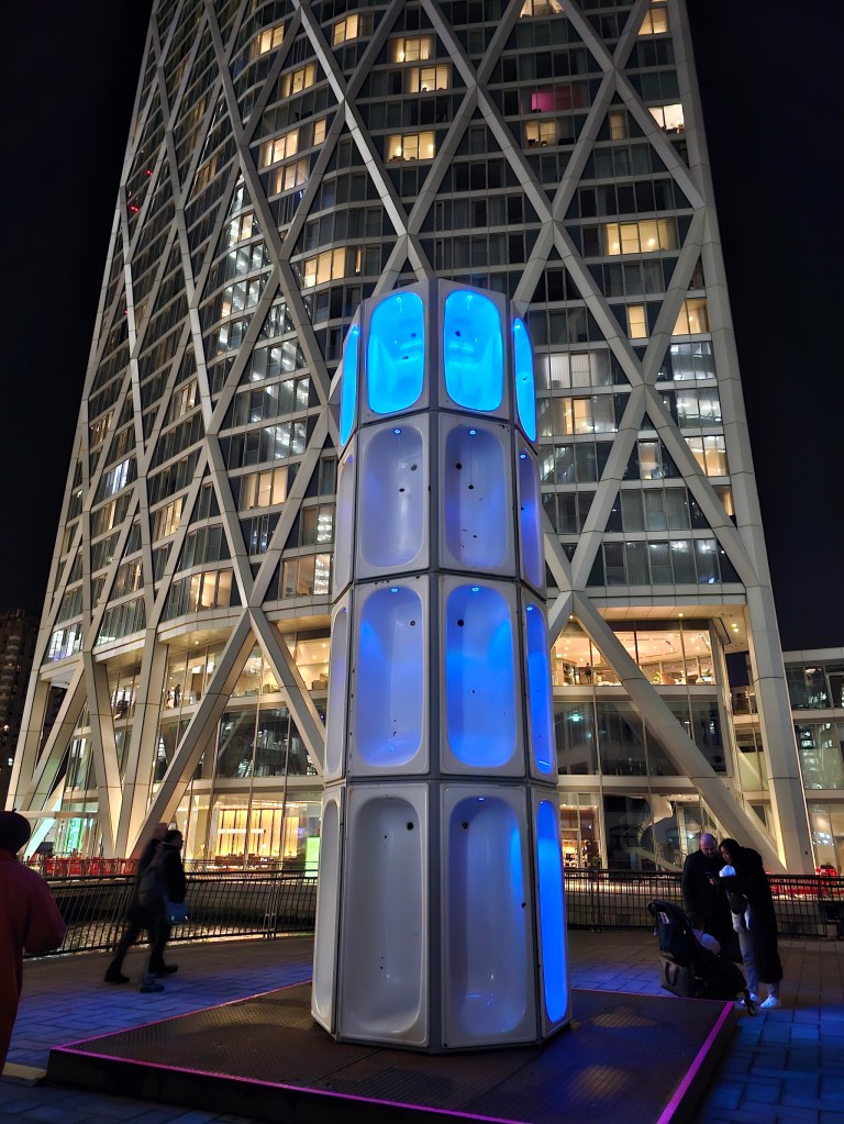 An abstract installation - a tower built out of bathtubs, some of them illuminated with blue lights.
