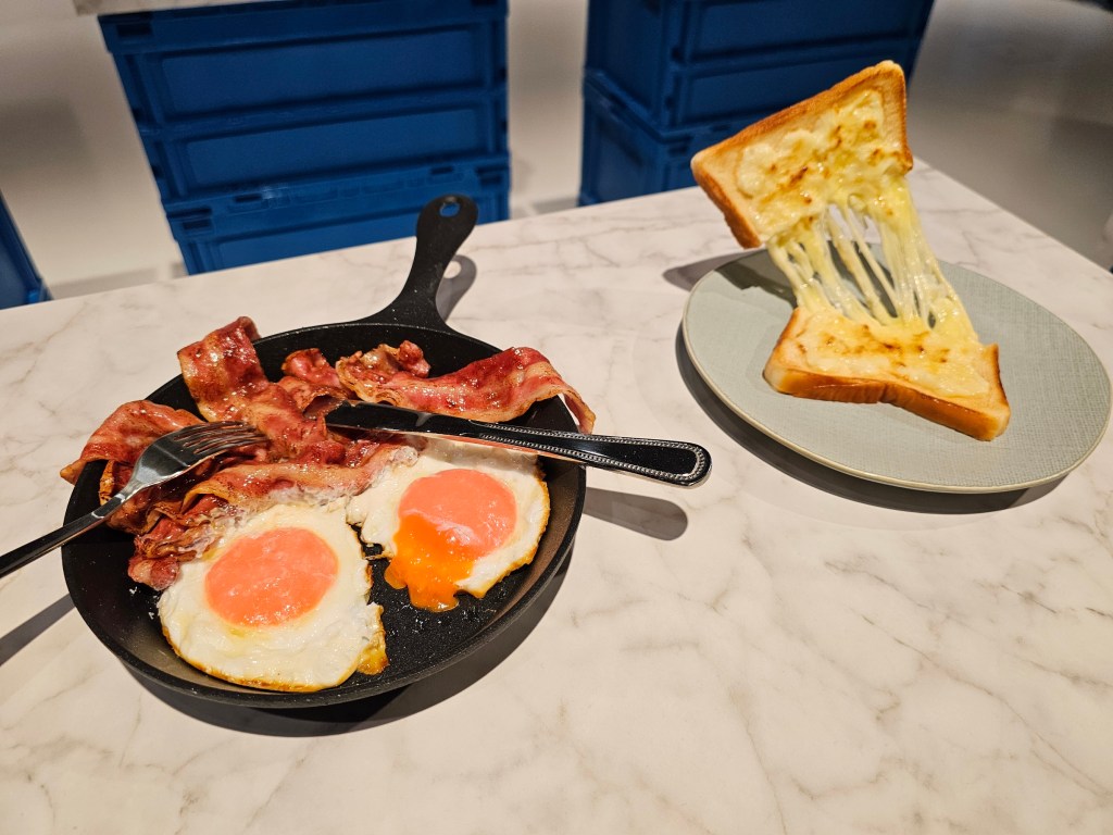 Food replicas: a frying pan with bacon and eggs, and cheese toastie.