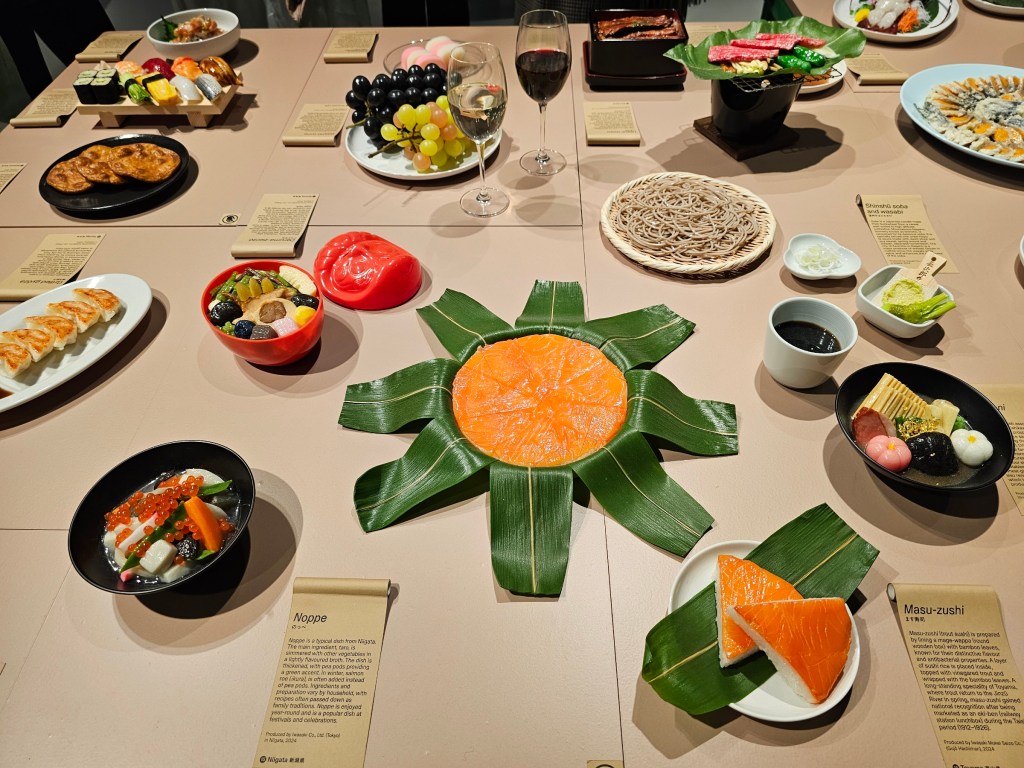 A table with several plates with Japanese food replicas.
