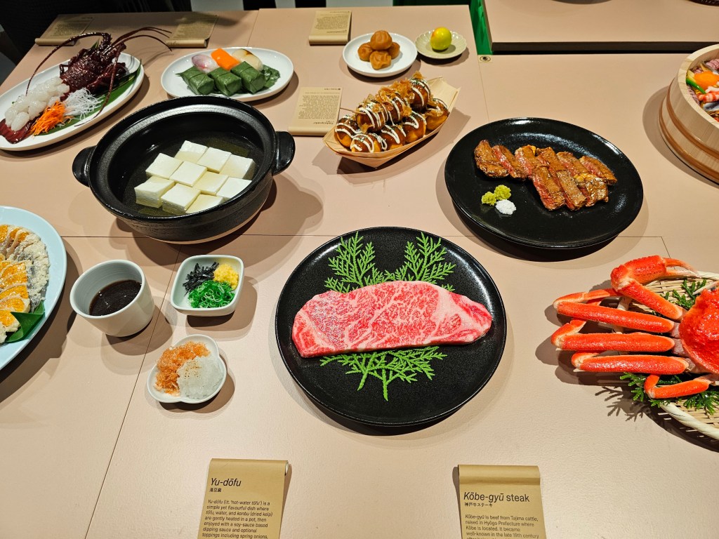 A table with several plates with Japanese food replicas.