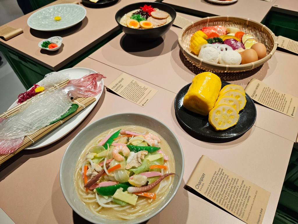A table with several plates with Japanese food replicas.