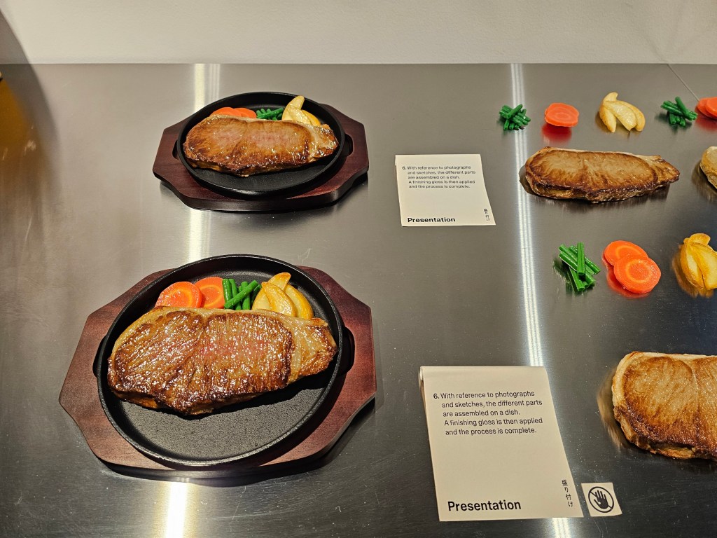 The final stage of creating a food replica: steak with carrots, beans and potatoes, served on a plate.