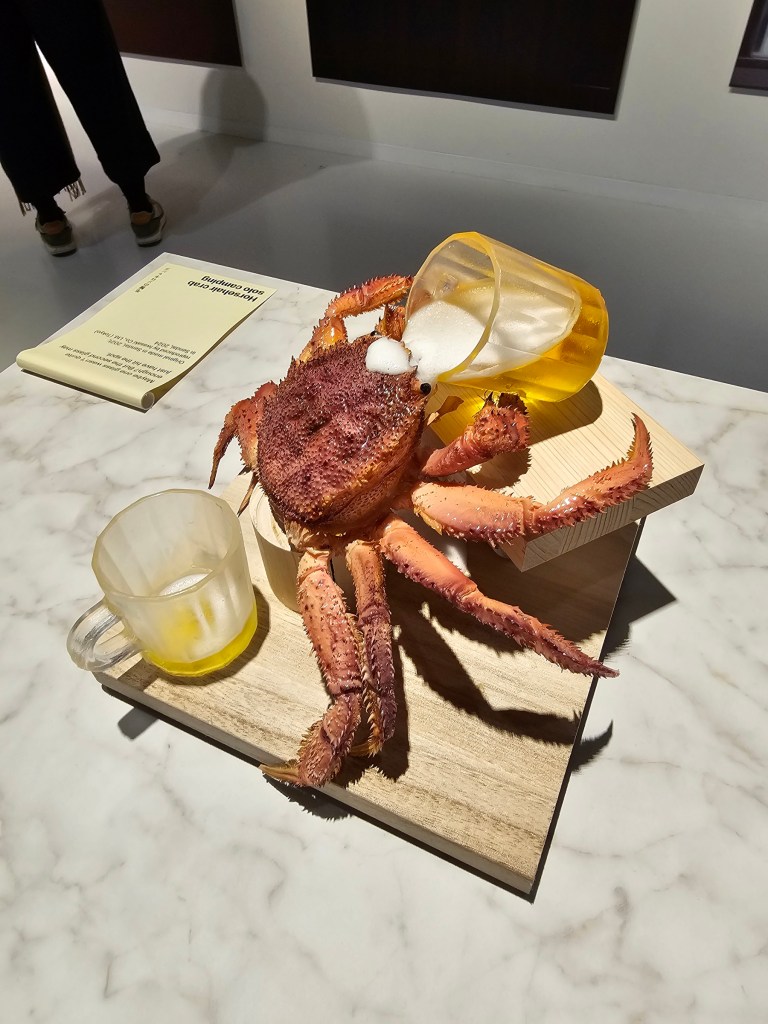 A large crab drinking a fake beer from a glass.