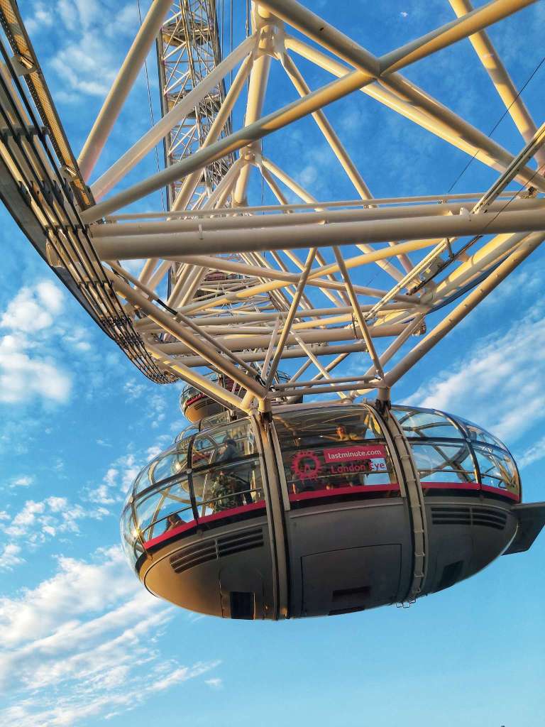 A close up of a capsule of London Eye Ferris wheel with blue skies in the background.
