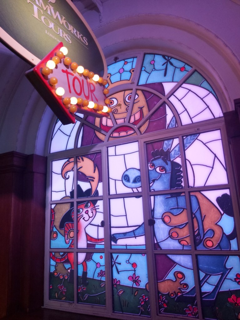 A modern stained glass featuring characters from an animated film: Shrek, Donkey and Puss in Boots.