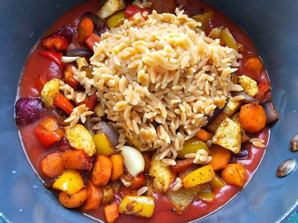 Roasted mixed vegetables in a pot, mixed with tomato passata and cooked red lentils.