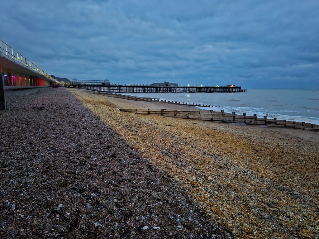 The beach in Hastings, at dusk. You can see Hastings Pier on the horizon.