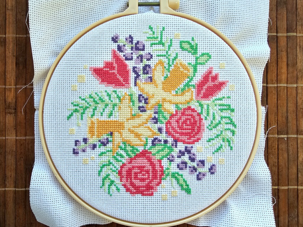 Finished cross stitch design featuring daffodils, roses and tulips.