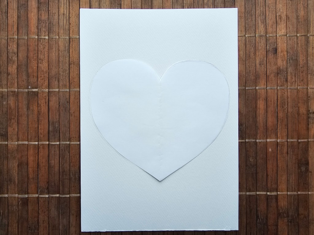 Heart template being fitted on a card blank.