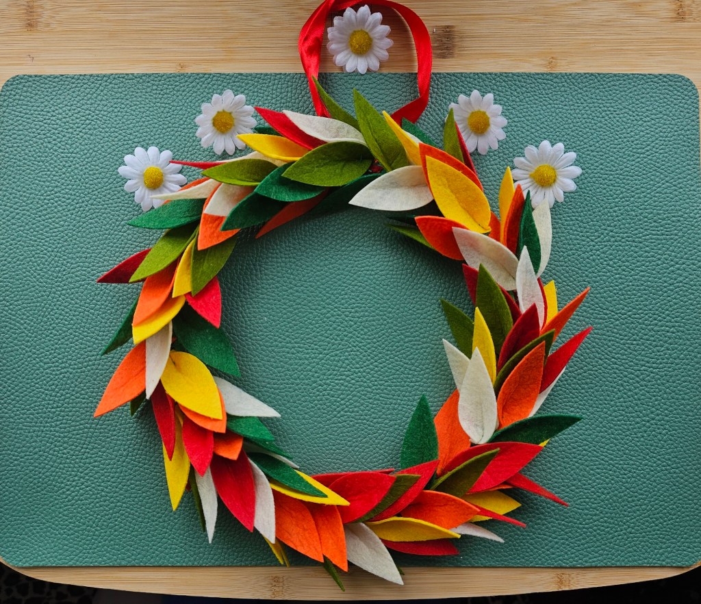Nearly finished DIY floral wreath with felt flowers. The base is done, but daisies aren't attached.