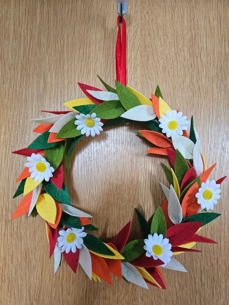 Finished DIY floral wreath with felt flowers, hanging on the door.