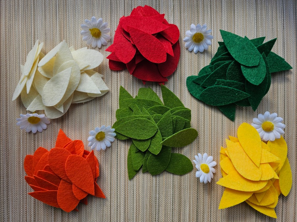 Six piles of felt petals: white, yellow, orange, red, light green and dark green.