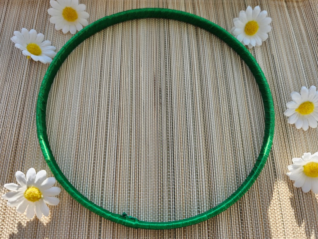 Wooden hoop wrapped with green ribbon.