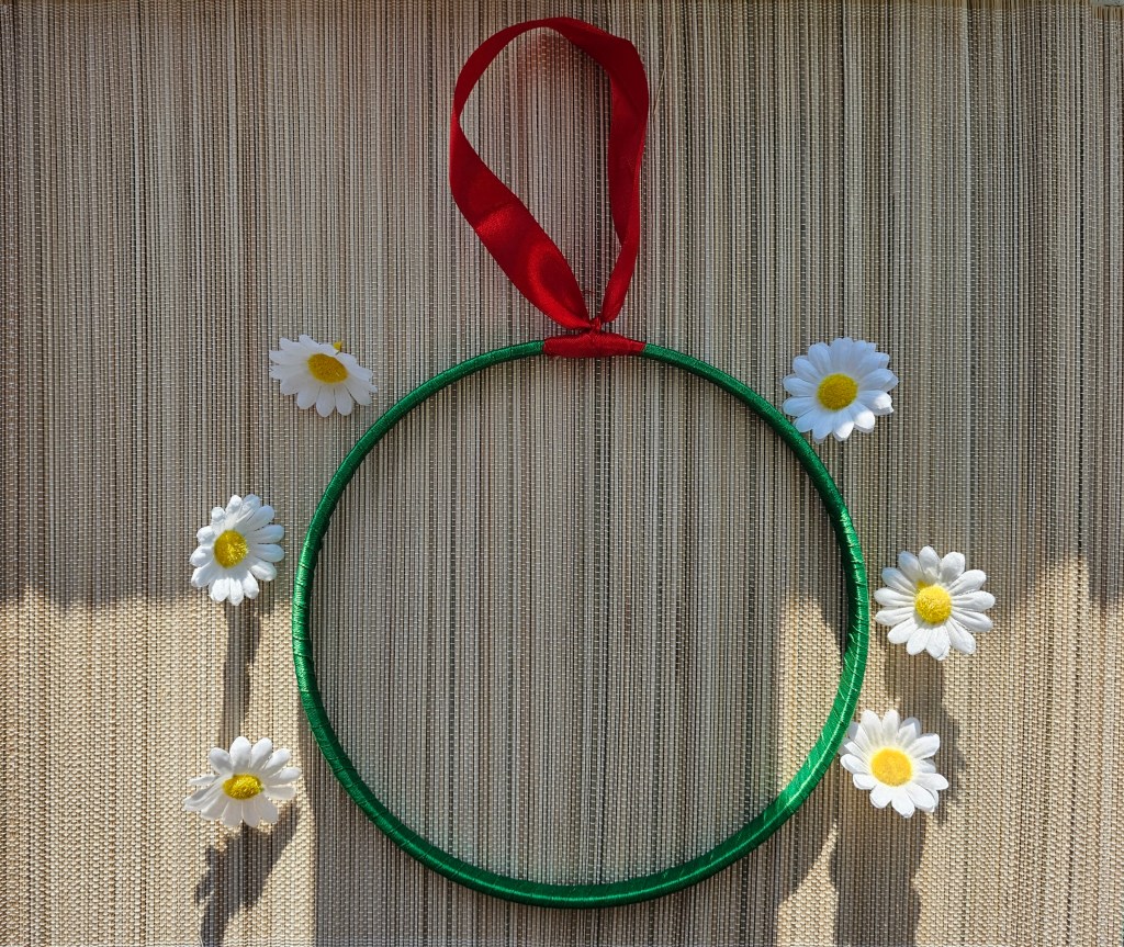 Wooden hoop wrapped with green ribbon. Hanging loop attached with red ribbon.