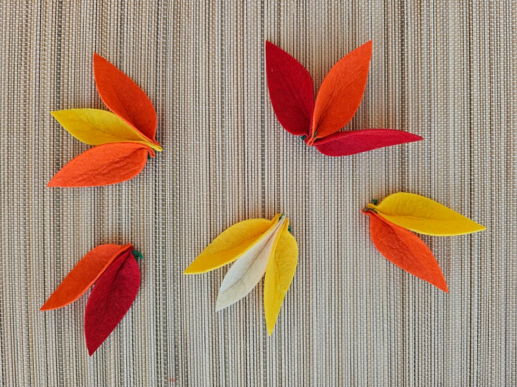 Six felt flower clusters in various colours. The felt petals are sewn together in groups of two or three.