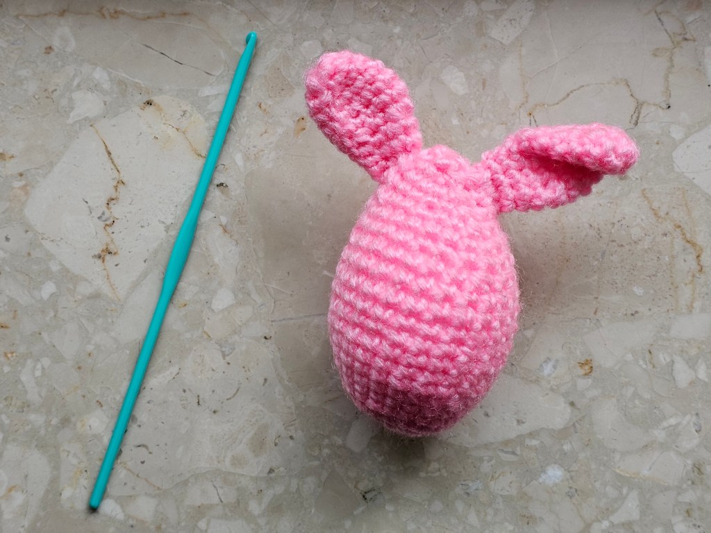 A pink crocheted Easter egg with bunny ears.