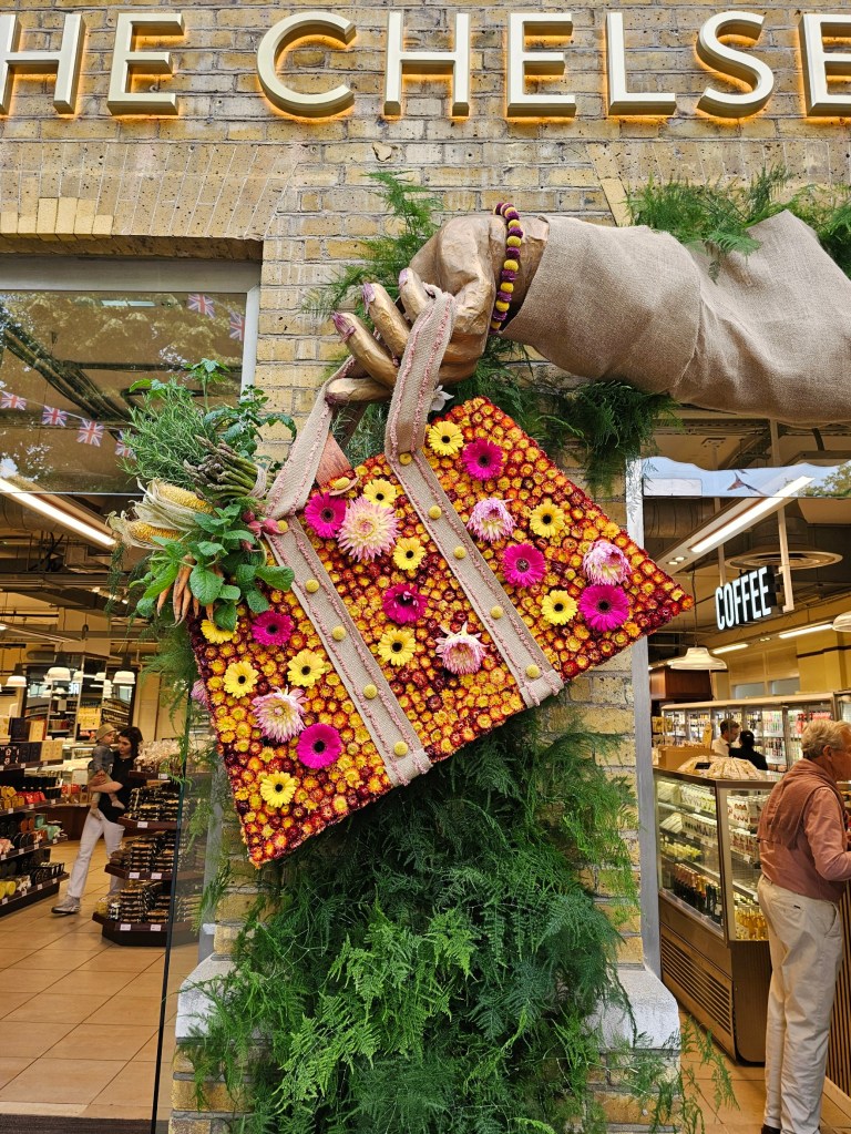 A small handbag made of flowers, on a wall next to a shop entrance.