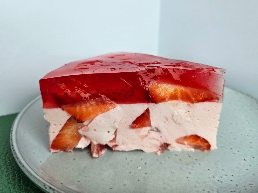 A slice of no-bake high protein strawberry cheesecake, on a plate.