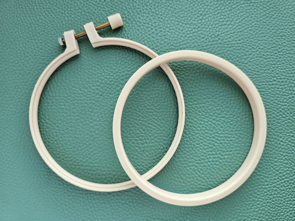 Plastic embroidery hoop separated into two parts.