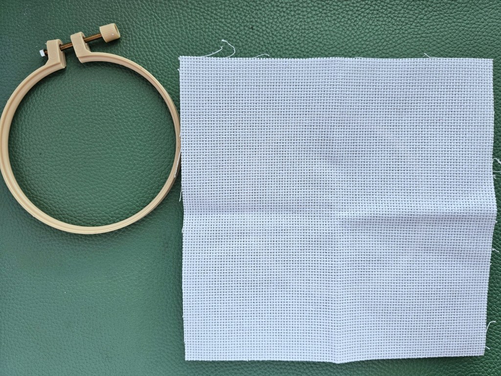 Blank aida next to an embroidery hoop.