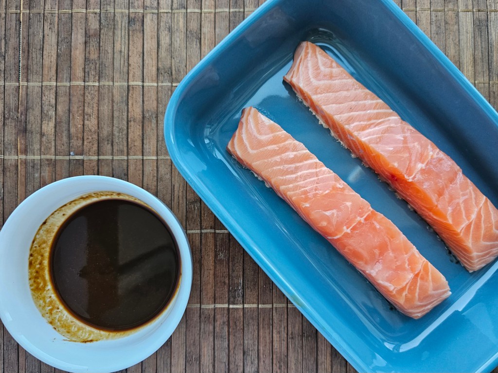 Two salmon fillets in an oven-proof dish. Miso marinade in a bowl.
