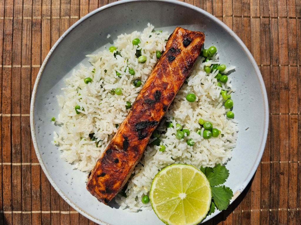 Miso Marinated Salmon With Coriander, Lime and Green Peas Rice, garnished with a lime.