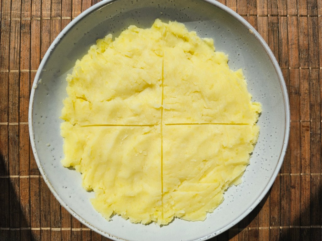 A plate with mashed potatoes. There is a cross drawn on the potatoes dividing them into 4 equal parts.