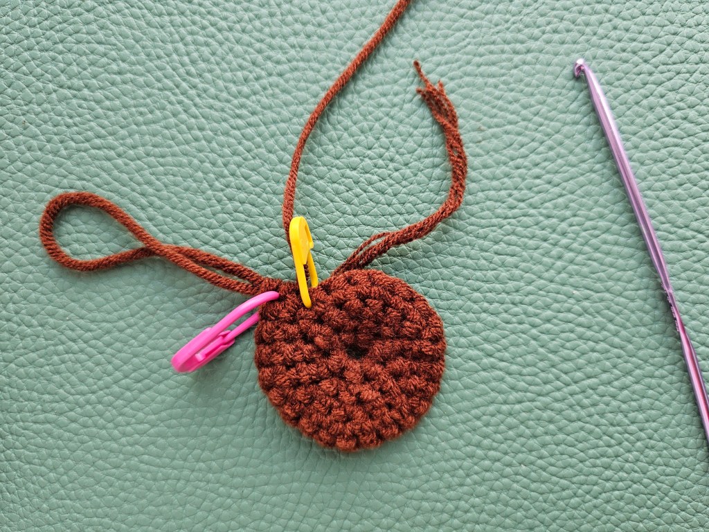 A small crocheted circle made with brown yarn.