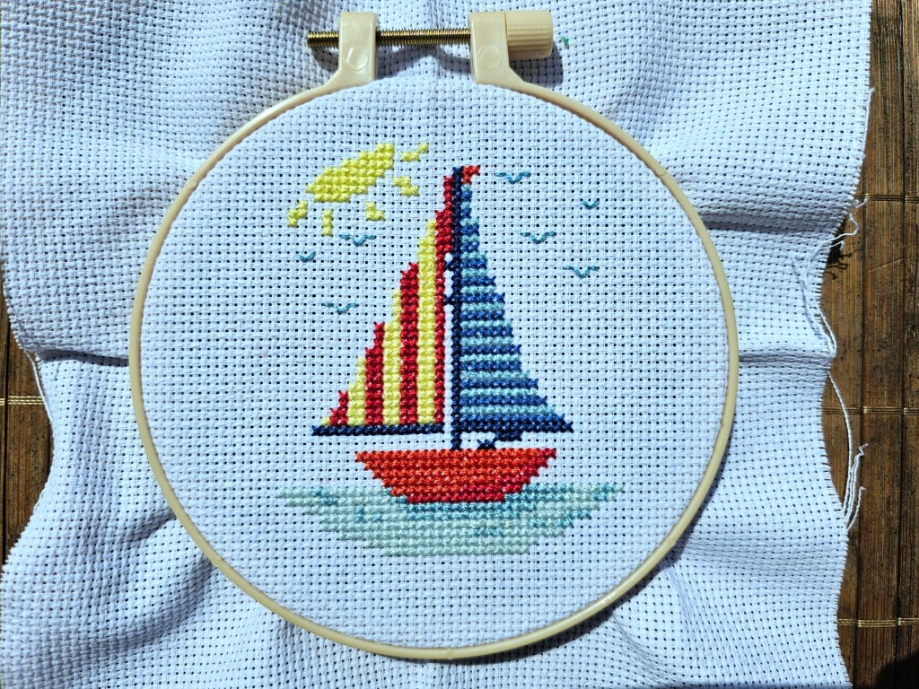 Completed cross stitch project with a small sailboat design.