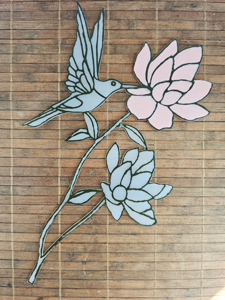 Partially finished fake stained glass ornament. One flower is painted with pink acrylic paint.