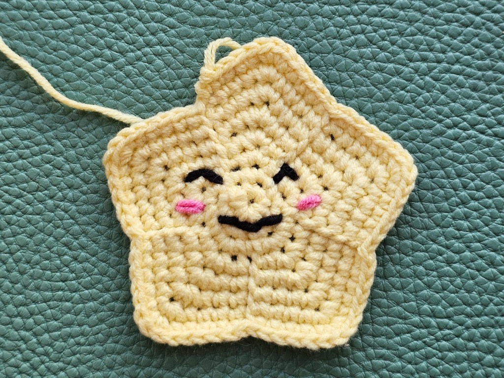 A crocheted star with embroidered cute face.