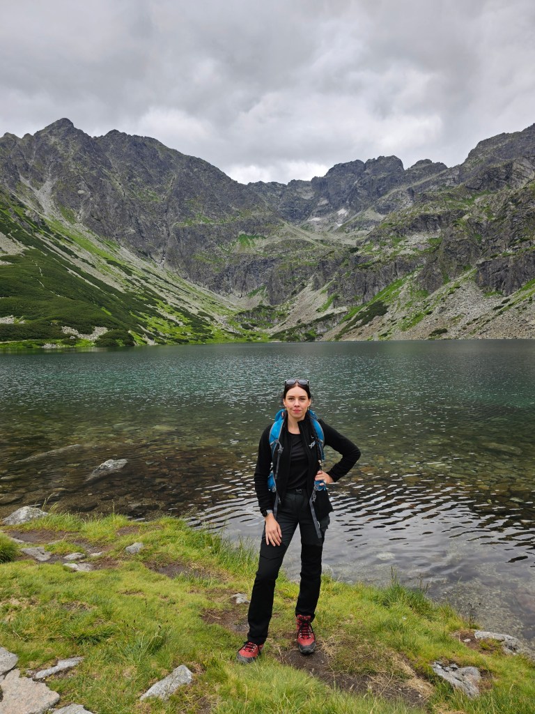 A person standing in front of Czarny Staw Gasienicowy in Tatra Mountains, Poland