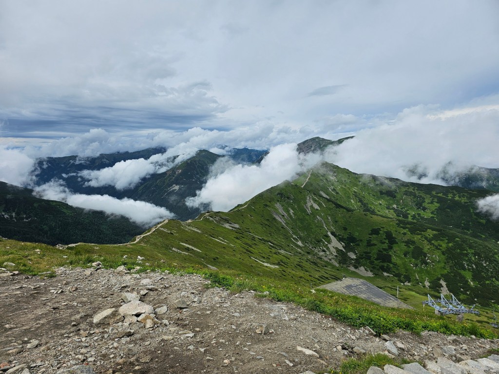 A path along the ridge of the mountains, seen from Kasprowy Wierch. Some of the mountains in the background are covered with clouds.