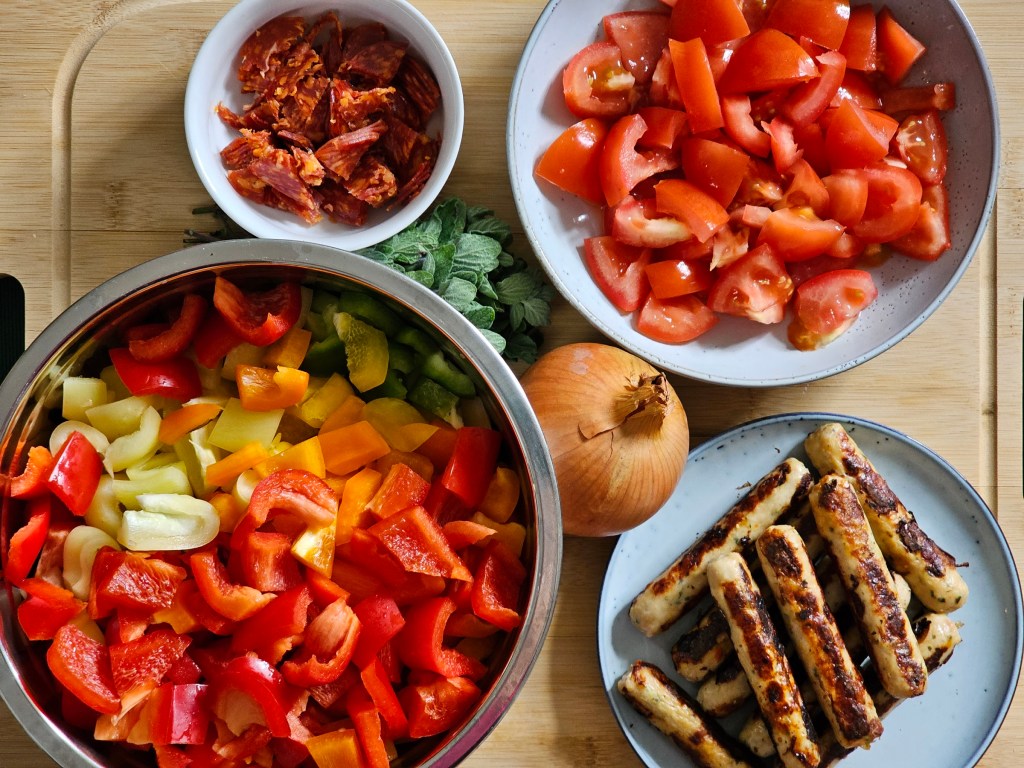 Ingredients for Polish leczo. Sausages, bell peppers, tomatoes, onion and oregano.