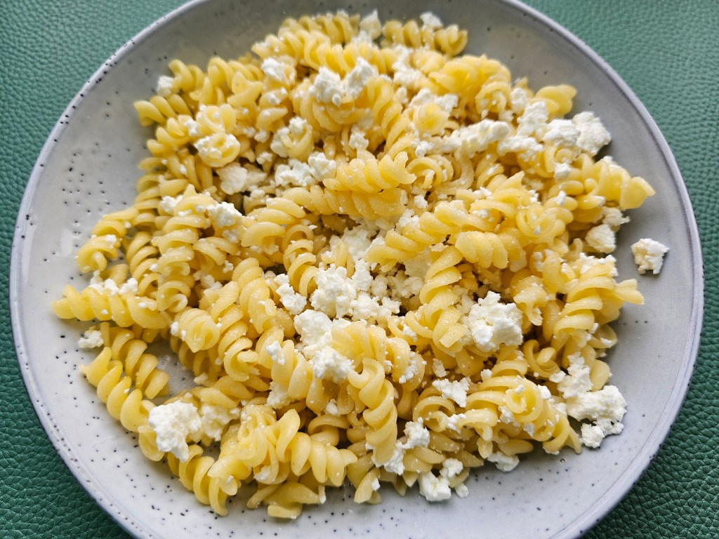 A plate with fusilli pasta sprinkled with crumbled curd cheese and sugar