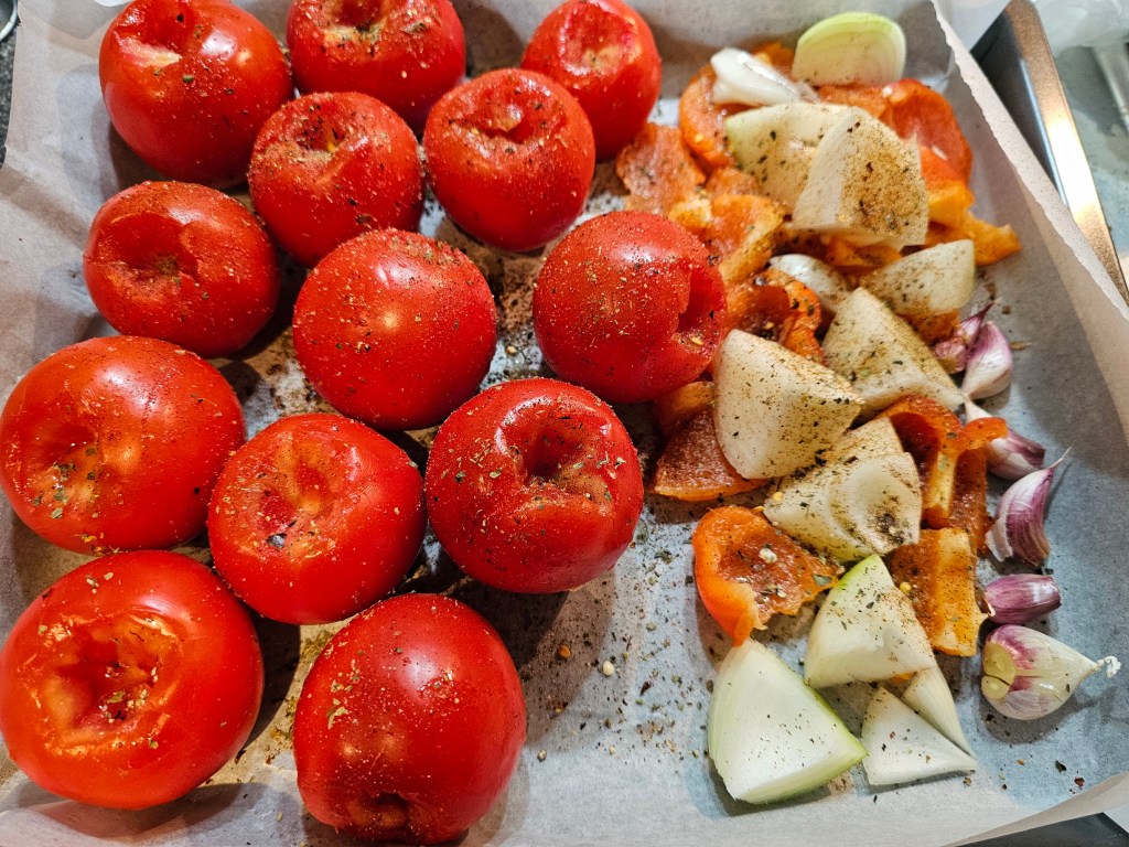 A baking tray with tomatoes, onion, bell pepper and garlic
