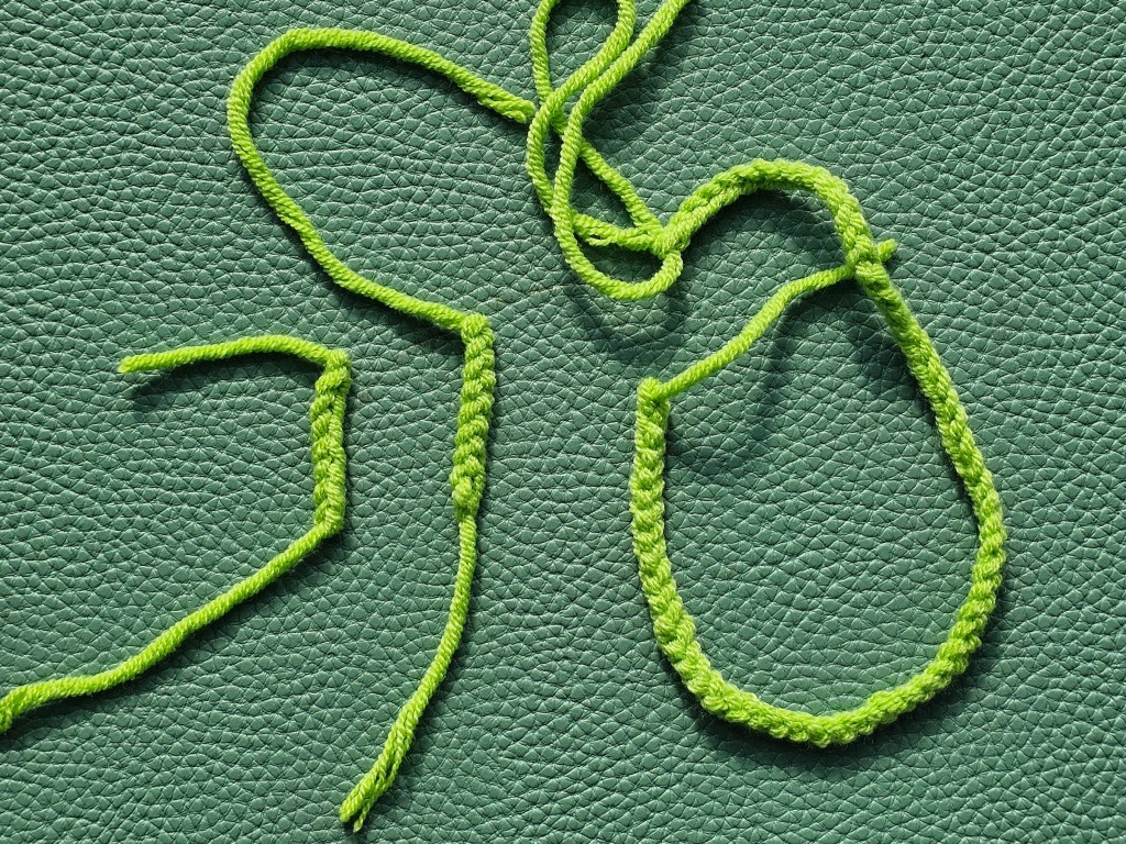 Three crocheted chains made with green yarn: two short ones and one long