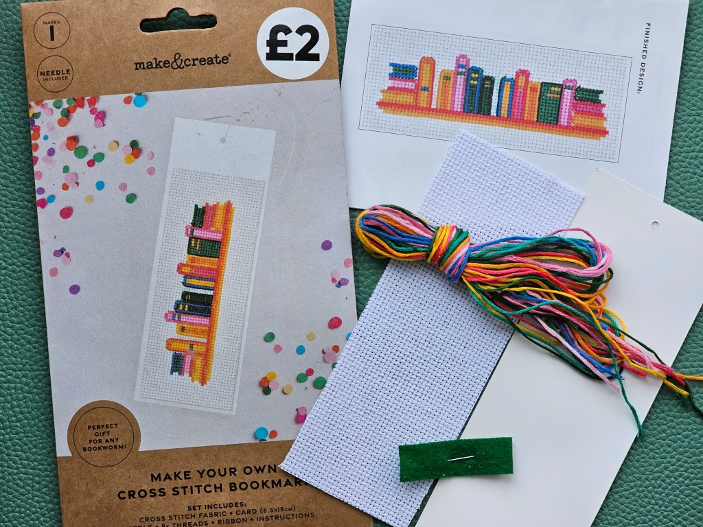 Contents of a DIY set for making a bookmark with a cross stitch design.