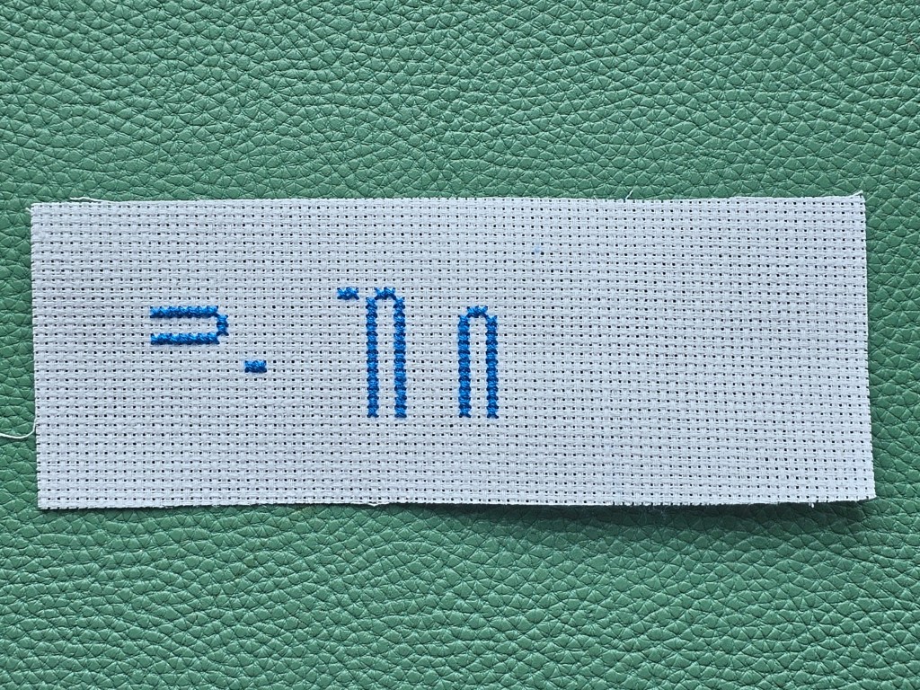 Partially completed cross stitch bookmark. Blue elements are done.