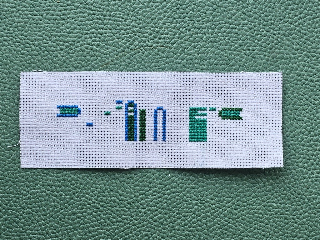 Partially completed cross stitch bookmark. Blue and green elements are done.