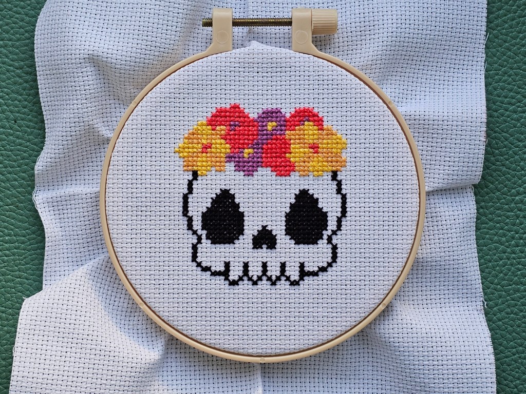 Nearly completed cross stitch design featuring a skull with flowers design