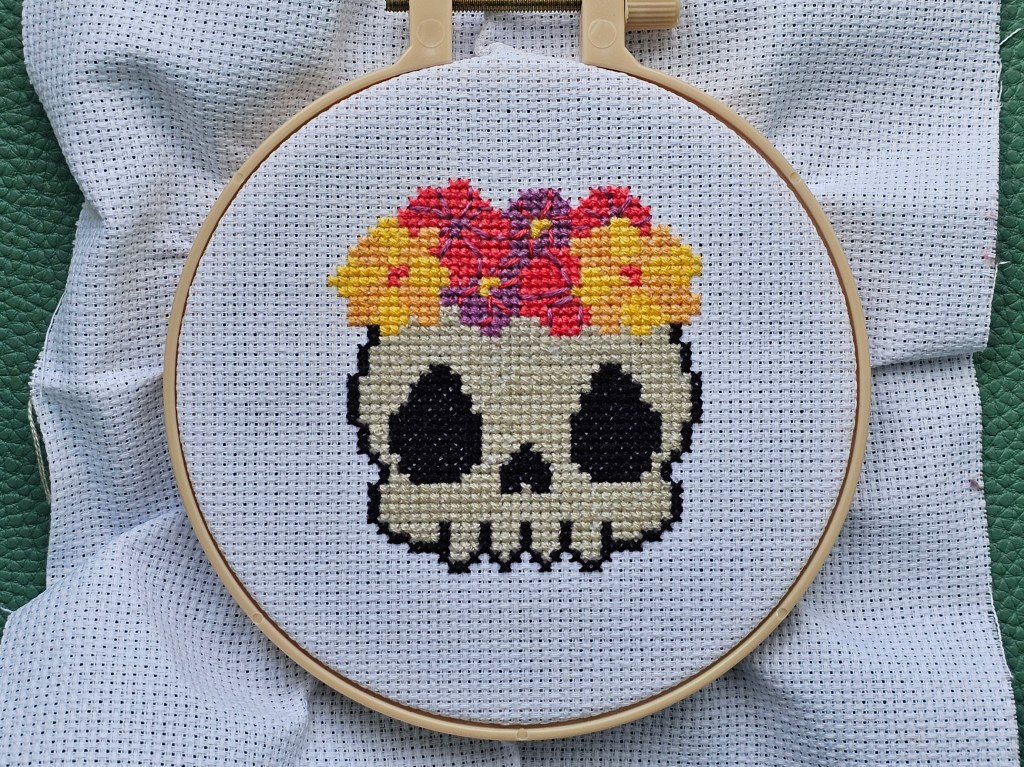 Completed cross stitch design featuring a skull with flowers design