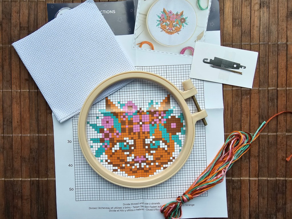 Partially finished mini cross stitch project featuring a floral cat.